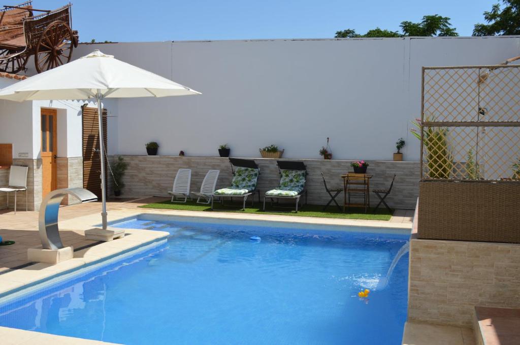 a swimming pool with an umbrella and chairs and a table at Casa Rural Los Pinillos in Motilleja