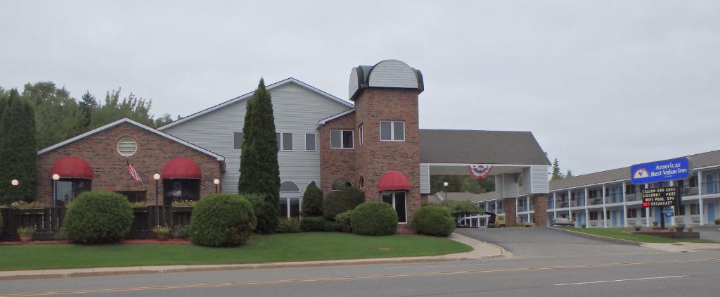 a large building with red awnings on a street at Americas Best Value Inn Saint Ignace in Saint Ignace