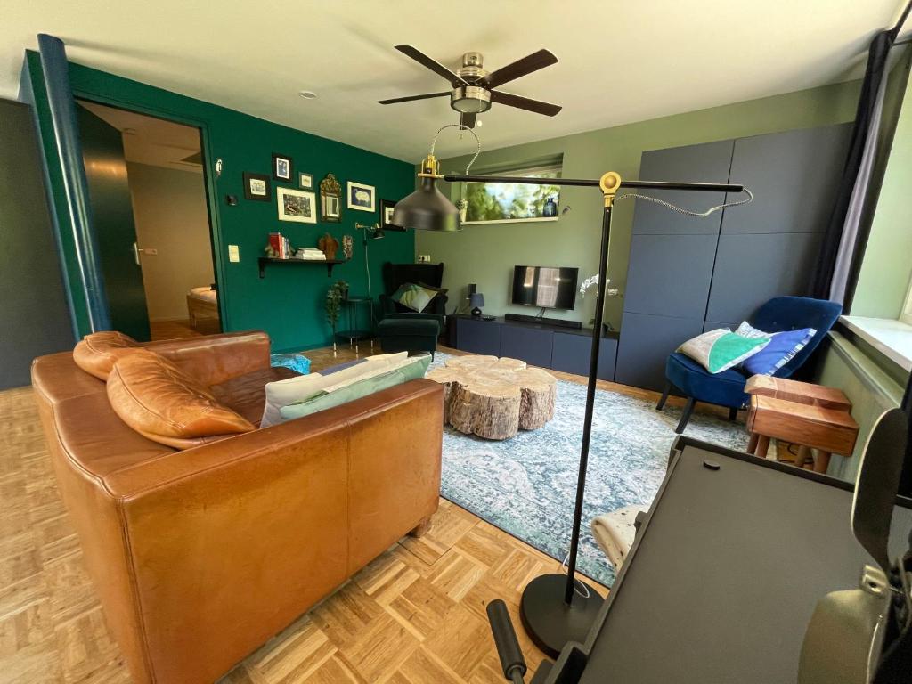 ein Wohnzimmer mit einem braunen Sofa und einer grünen Wand in der Unterkunft Ivy Cottage near Amsterdam in Oudendijk