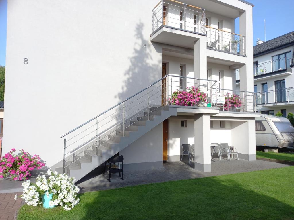 een wit gebouw met trappen en bloemen in een tuin bij Dom Hermana in Mrzeżyno