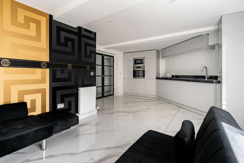 ein Wohnzimmer mit einem schwarzen Sofa und einer Küche in der Unterkunft Modern 3BHK near Edinburgh zoo in Edinburgh