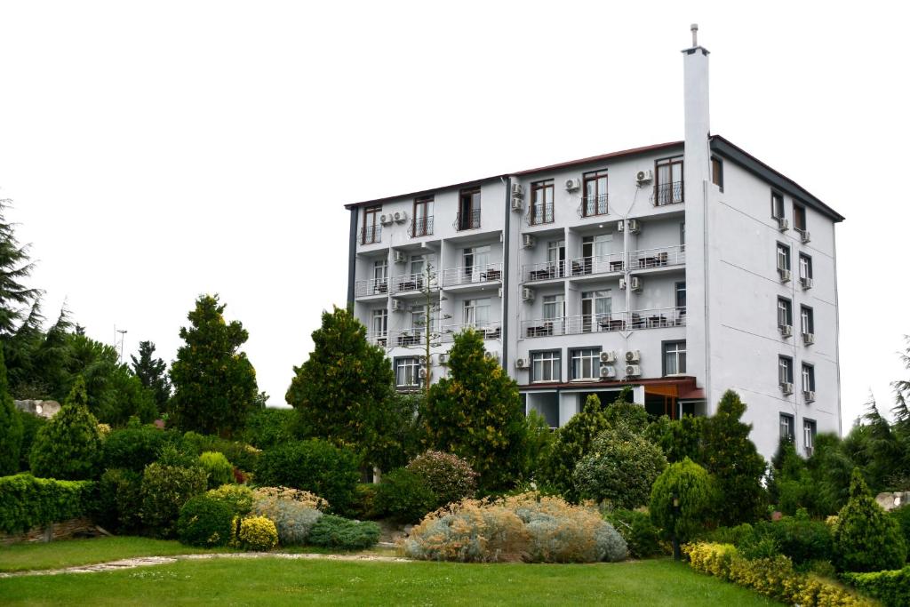a white building with a garden in front of it at Sahil Hotel Pendik in Tuzla