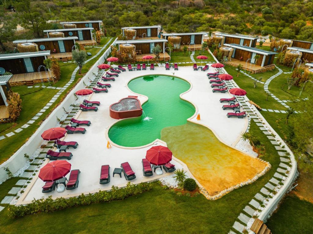 an aerial view of a resort pool with red umbrellas and chairs at Mossa Afkule Kayaköy in Fethiye