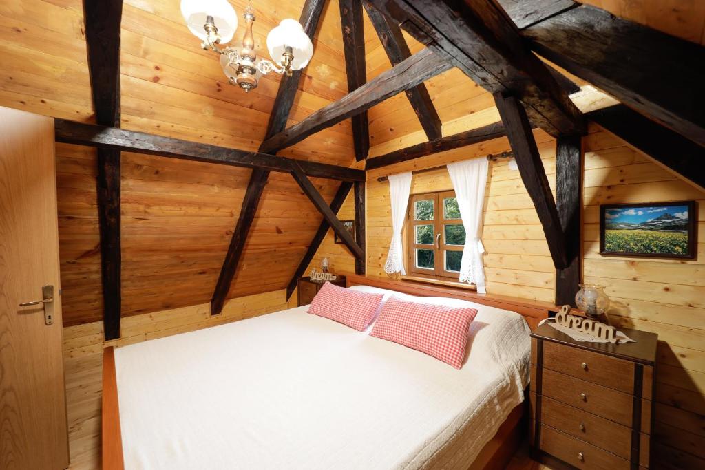 1 dormitorio con 1 cama blanca en una habitación de madera en Kuća za odmor Poljanica Okićka, en Jastrebarsko