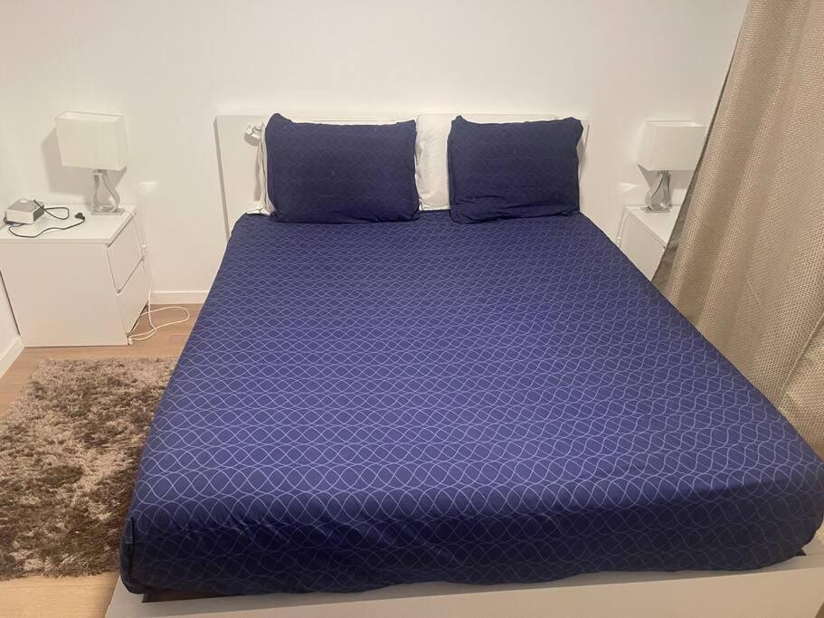 Cama morada con almohadas azules en una habitación en Logement YJR, en Pierrefitte-sur-Seine