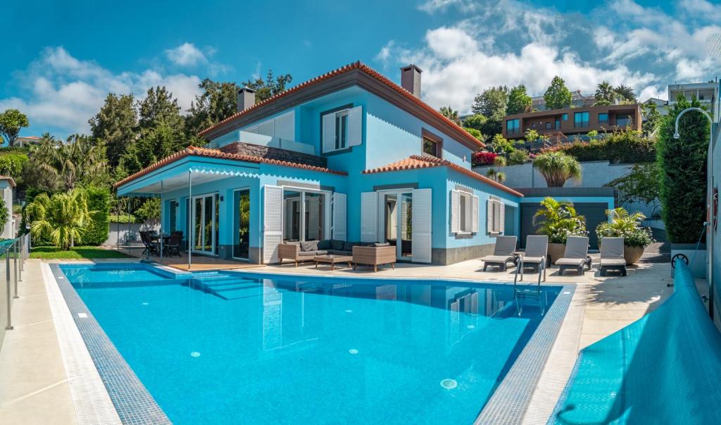 a villa with a swimming pool in front of a house at Villa Loureiro Palace With Soccer Field in São Gonçalo