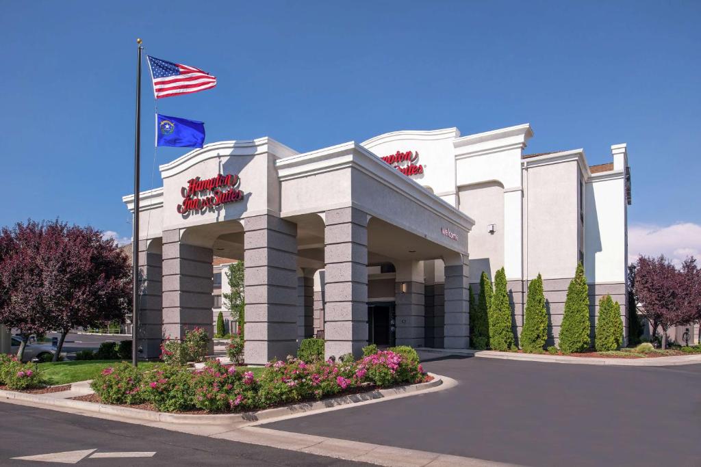 a white building with an american flag in front of it at Hampton Inn & Suites Carson City in Carson City