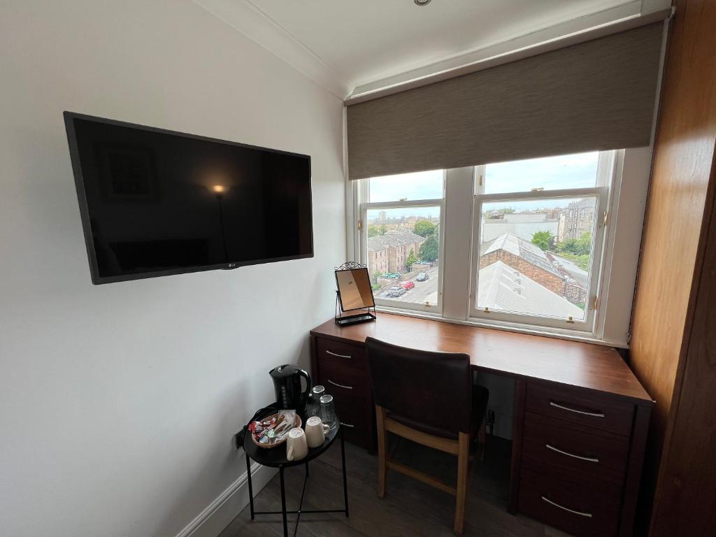 Zimmer mit einem Schreibtisch, einem TV und einem Fenster. in der Unterkunft Cosy Double Room City Centre in Edinburgh