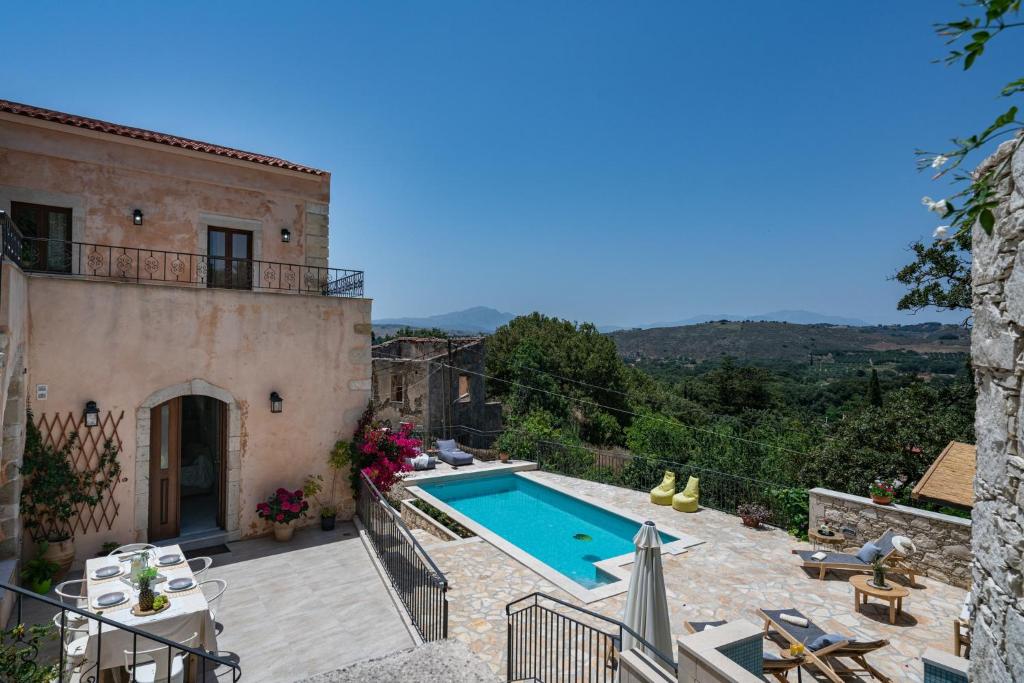 a villa with a swimming pool in front of a house at Butterfly, a historical villa with pool & hot tub! in Arménoi