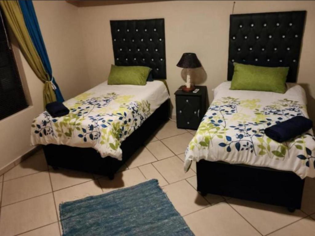 a bedroom with two beds and a lamp and a rug at The Sanctuary - Self Catering Accommodation in Mtubatuba