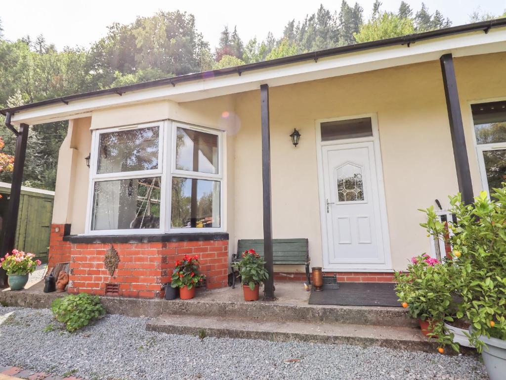 une petite maison avec une porte et un banc dans l'établissement Trem Y Don, à Dolgarrog