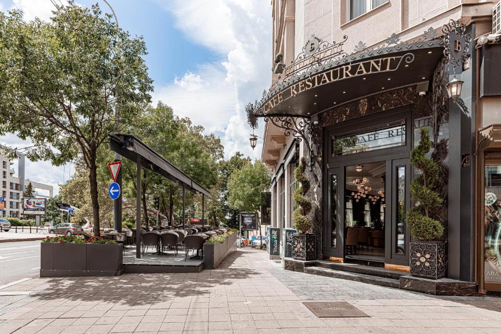 uma rua com um restaurante com cadeiras em frente a um edifício em Hotel Balkan em Belgrado
