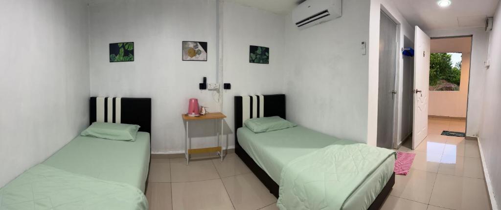 two beds in a room with white walls at Sungai endau bilik homestay in Kuala Rompin