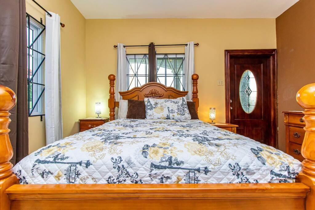 a bedroom with a bed with a blue and white comforter at J&R Sunshine Retreat in Spanish Town