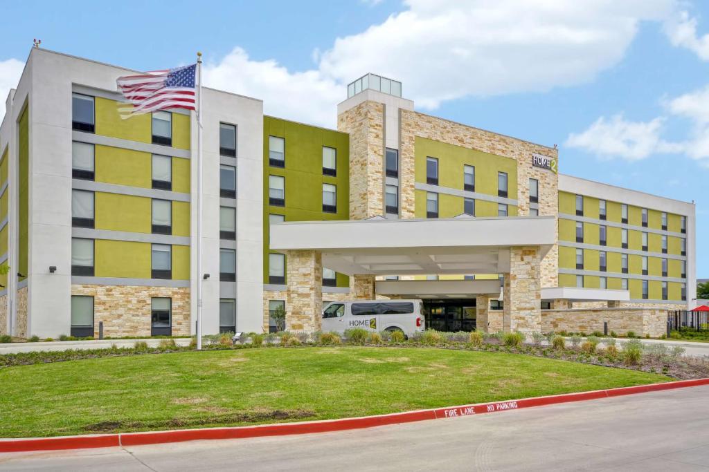 un immeuble de bureaux doté d'un drapeau américain devant lui dans l'établissement Home2 Suites By Hilton Dallas Addison, à Addison