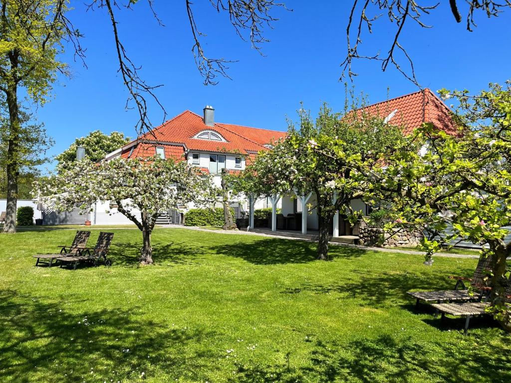 ein Haus mit einem grünen Garten mit Bäumen und Bänken in der Unterkunft Landidyll Elmenhorst Wohnung 01 in Elmenhorst