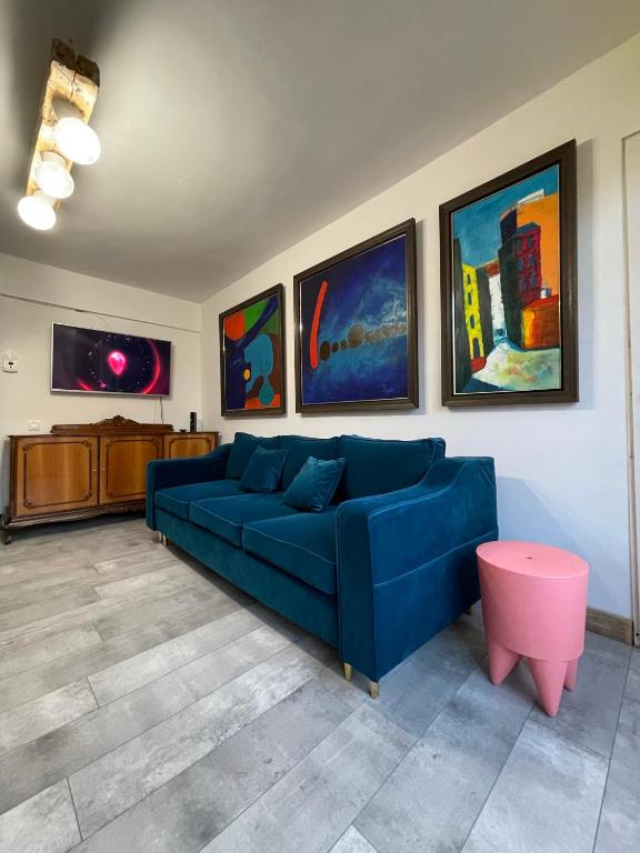 a living room with a blue couch and paintings at Art Apartments Govora Cluj in Cluj-Napoca