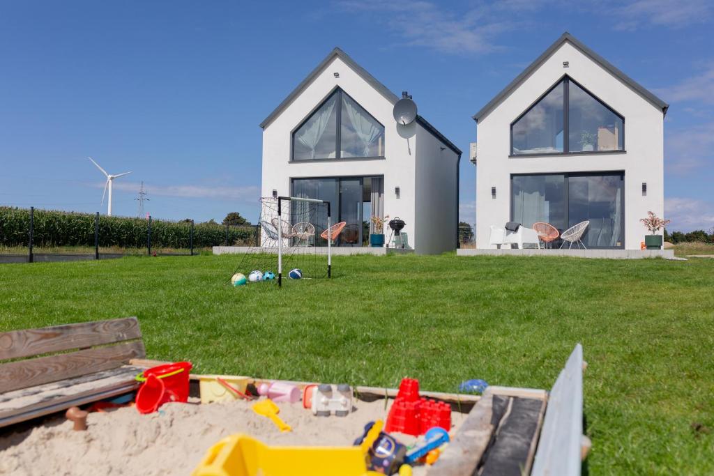 uma casa com uma caixa de areia em frente a uma casa em Pogodne domki em Swarzewo