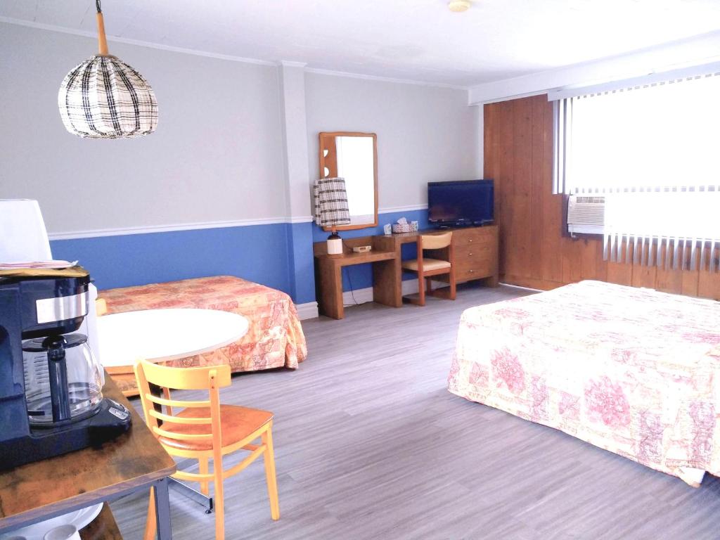 a hotel room with two beds and a television at Motel & Camping Fort Ramsay in Gaspé