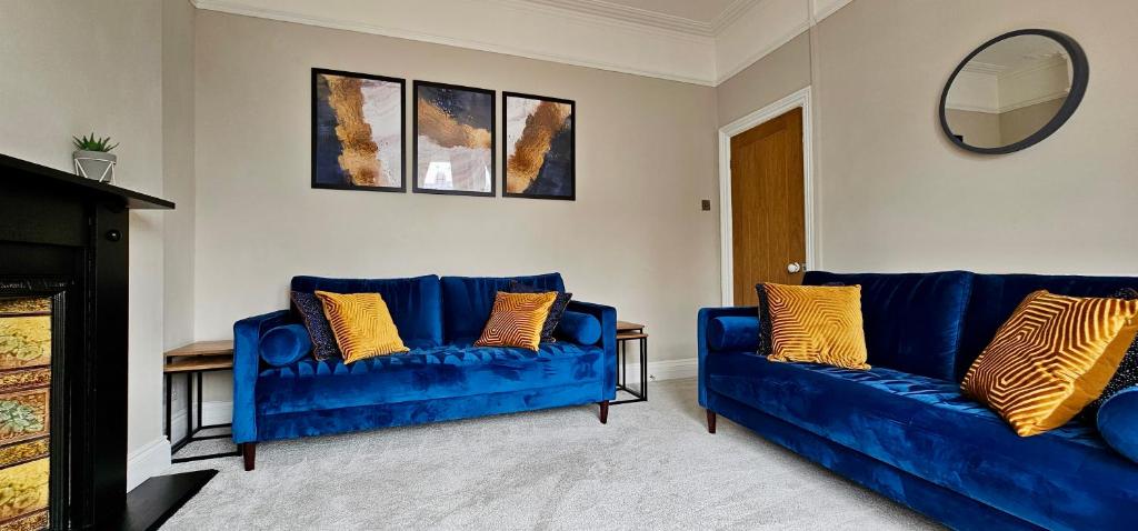 een woonkamer met twee blauwe banken en een spiegel bij Habershon by Switchback Stays in Cardiff