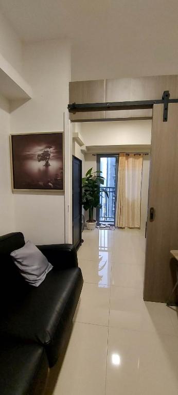 sala de estar con sofá negro y TV en 2 Bedroom with Balcony/ Family Room, en Manila