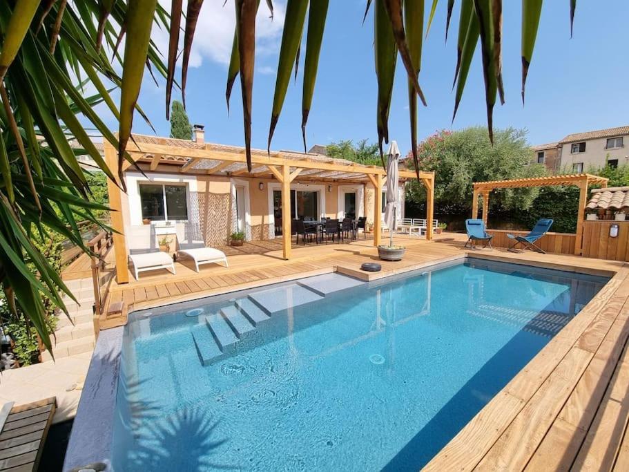 a pool with a wooden deck and a house at Villa spacieuse Piscine, terrain de petanque in Villeveyrac