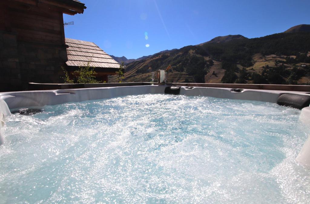 una piscina profunda con jacuzzi y montañas en el fondo en Chalet with Ski Slope Views, Jacuzzi & Cinema Room en Vars