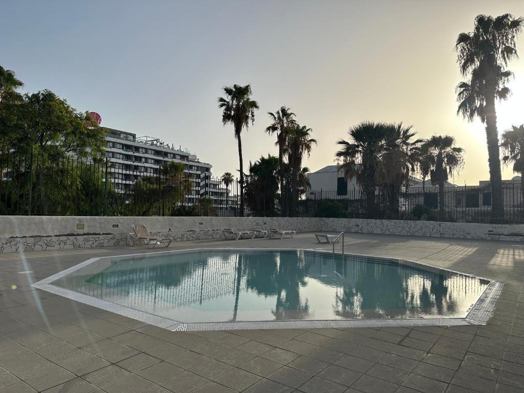 una piscina en un patio con palmeras en Las Americas Tenerife, en Arona