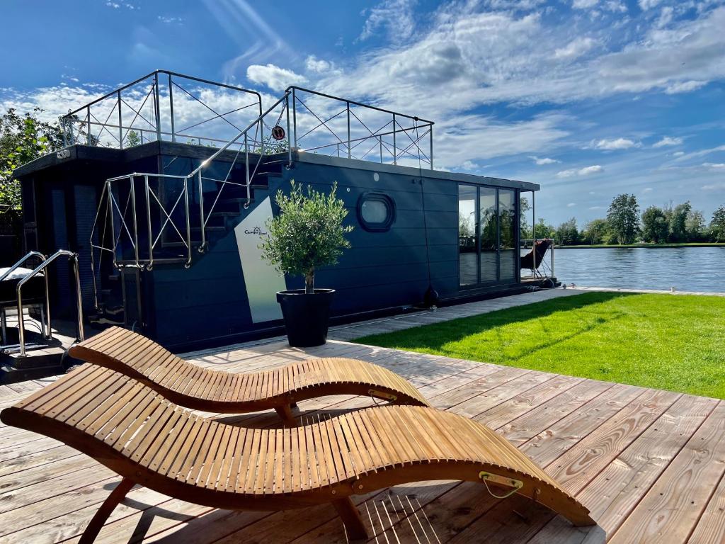 un banco de madera sentado en una terraza junto a una casa en NEW - Little Asia - Stunning Boathouse on al lake Near Amsterdam, en Vinkeveen
