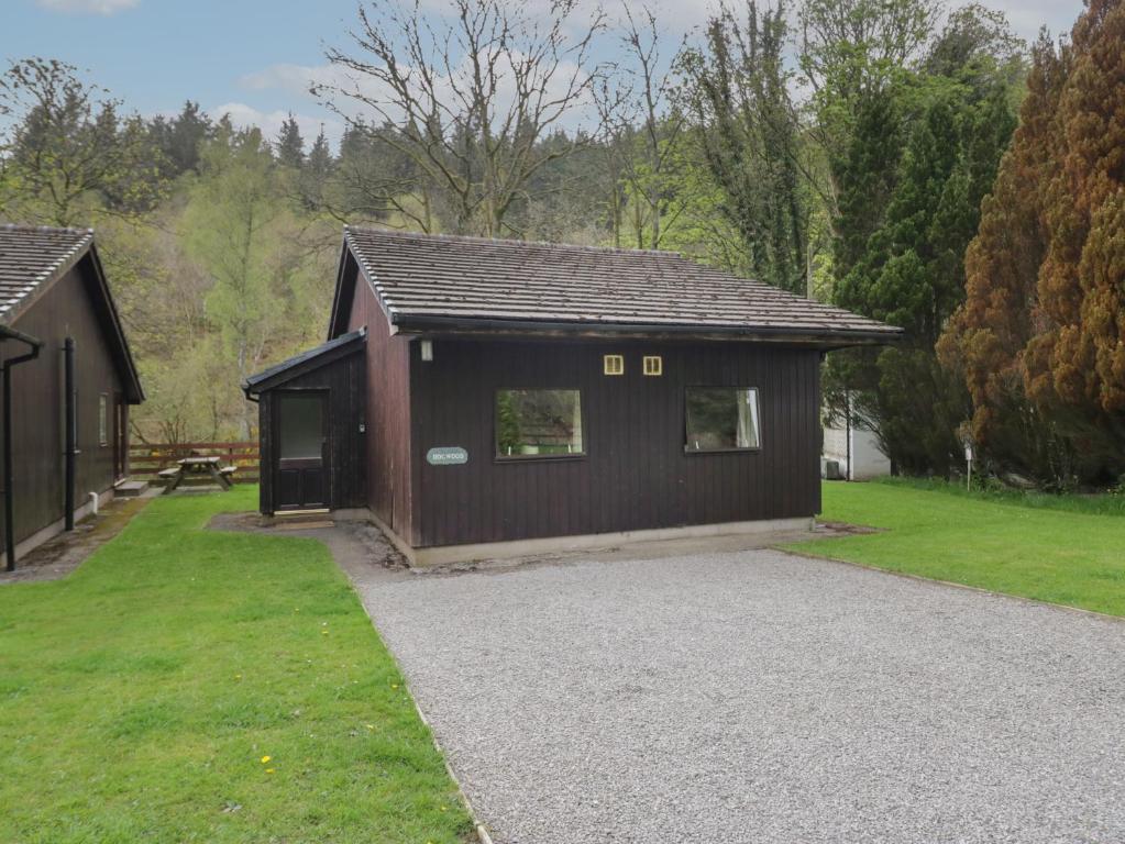 a small brown building with a grass yard at Dogwood Timber Lodge in Keswick
