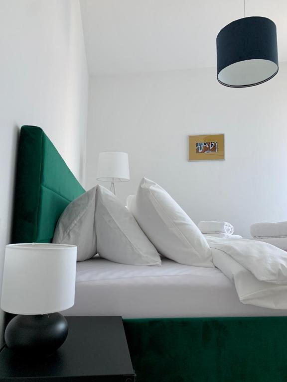 a bed with white pillows and a lamp on a table at Ap-art-mán 08 in Mikulov