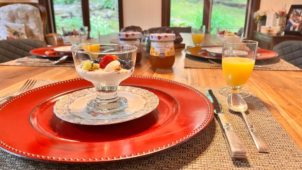 a wooden table with a plate with a bowl of ice cream and a drink at PETIT COIN DE PARADIS in Sainte Anne des Lacs