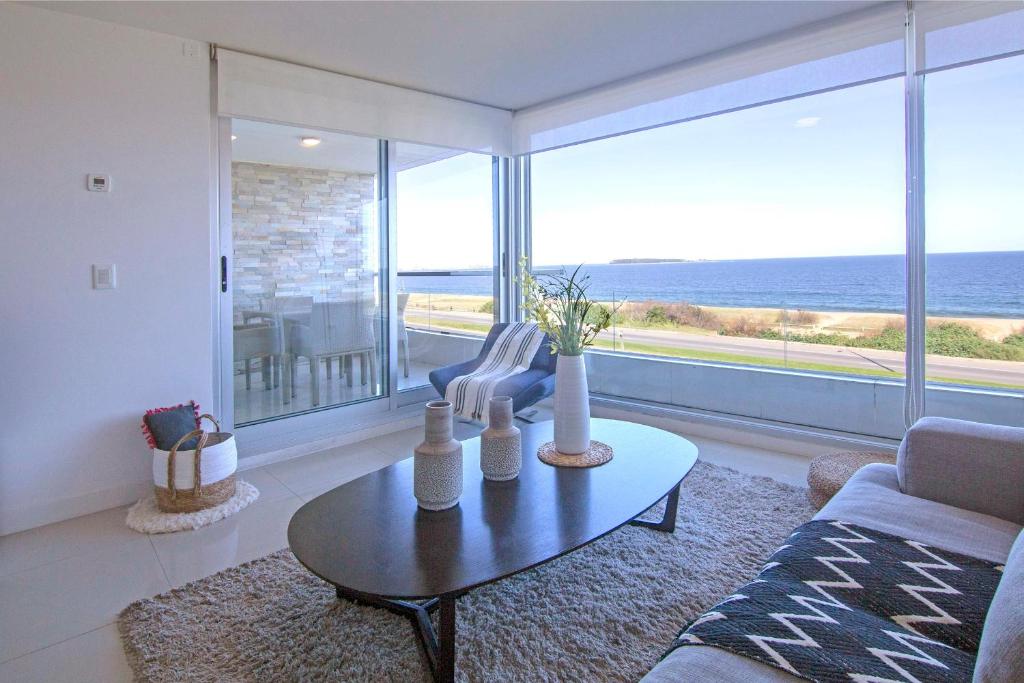 プンタ・デル・エステにあるOceana Suites en Lumiere, frente a playa Mansaのリビングルーム(テーブル付)が備わり、海の景色を望めます。