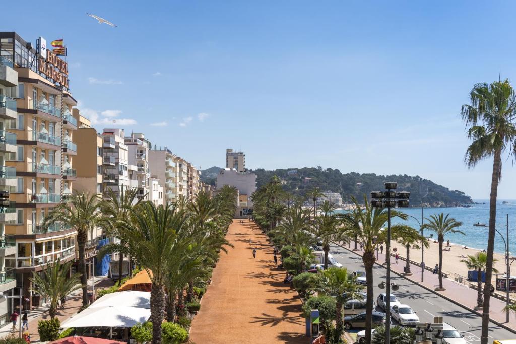 a street lined with palm trees next to a beach at Hotel Marsol in Lloret de Mar