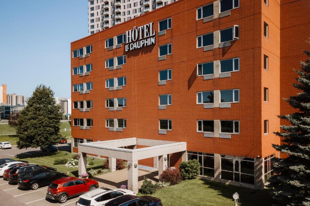 a large red brick building with a parking lot at Le Dauphin Montréal-Longueuil in Longueuil