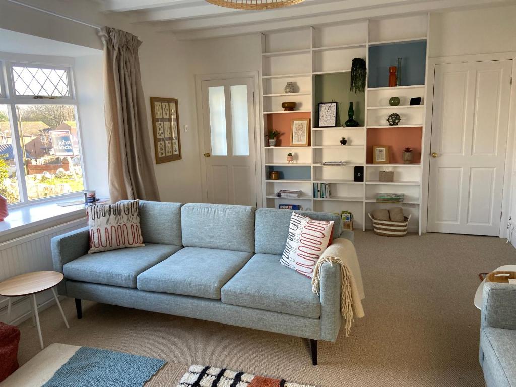 a living room with a blue couch and a window at Seaglass Cottage Mumbles in Oystermouth