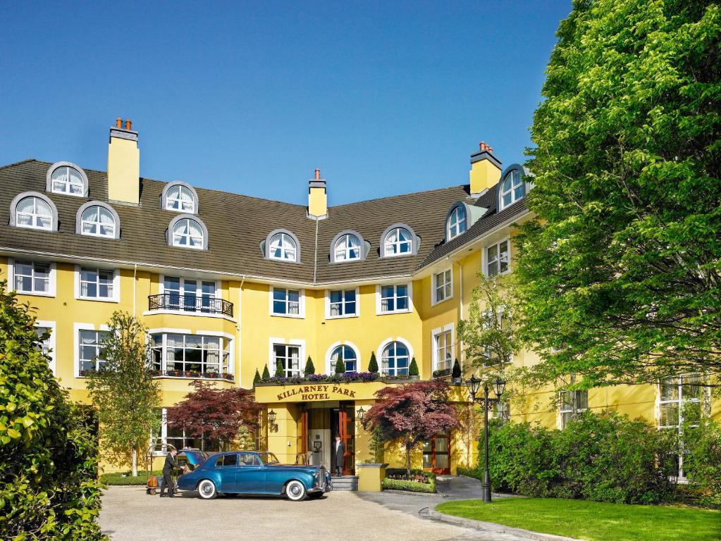 un edificio amarillo con un coche aparcado delante de él en The Killarney Park en Killarney