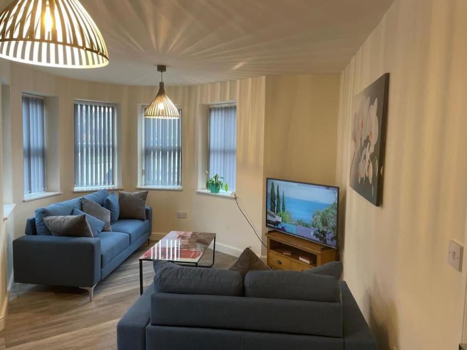 Lovely 2 bedroom apartment in Fleetwood في فليتوود: غرفة معيشة مع أريكة زرقاء وتلفزيون