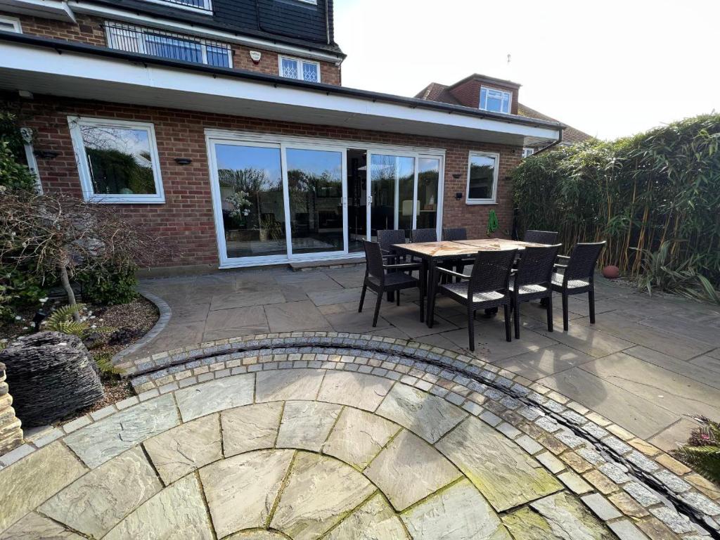 a patio with a table and chairs in front of a house at Luxury 4 bedroom house in Mill Hill in Mill Hill