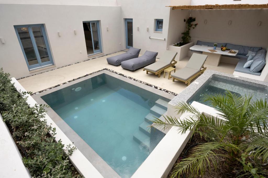uma piscina num pátio com uma mesa e cadeiras em Tholaki luxury home em Kamari