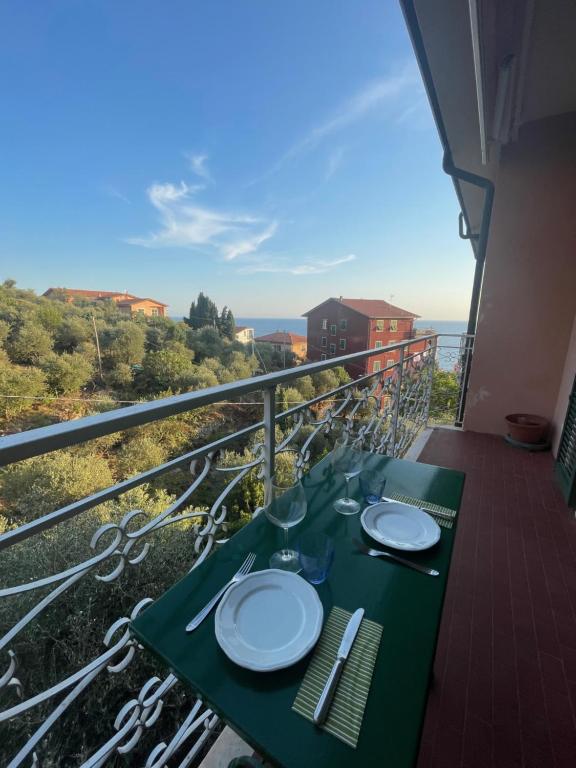 een tafel met borden en wijnglazen op een balkon bij Appartamento vista mare e uliveto a Tellaro in Tellaro