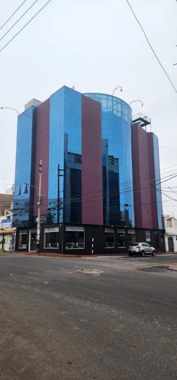 a large glass building with a car parked in front of it at Hotel PLATINIUM in Tacna