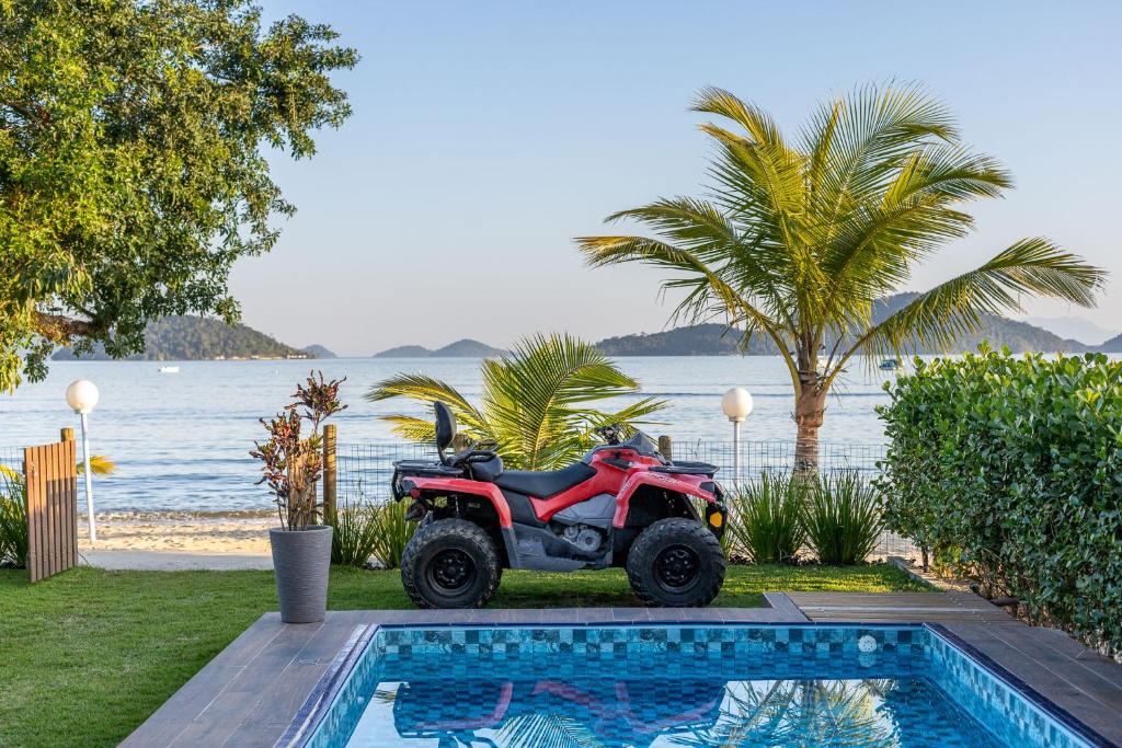 a red atv parked next to a swimming pool at Casa Na Praia em Angra dos Reis in Angra dos Reis