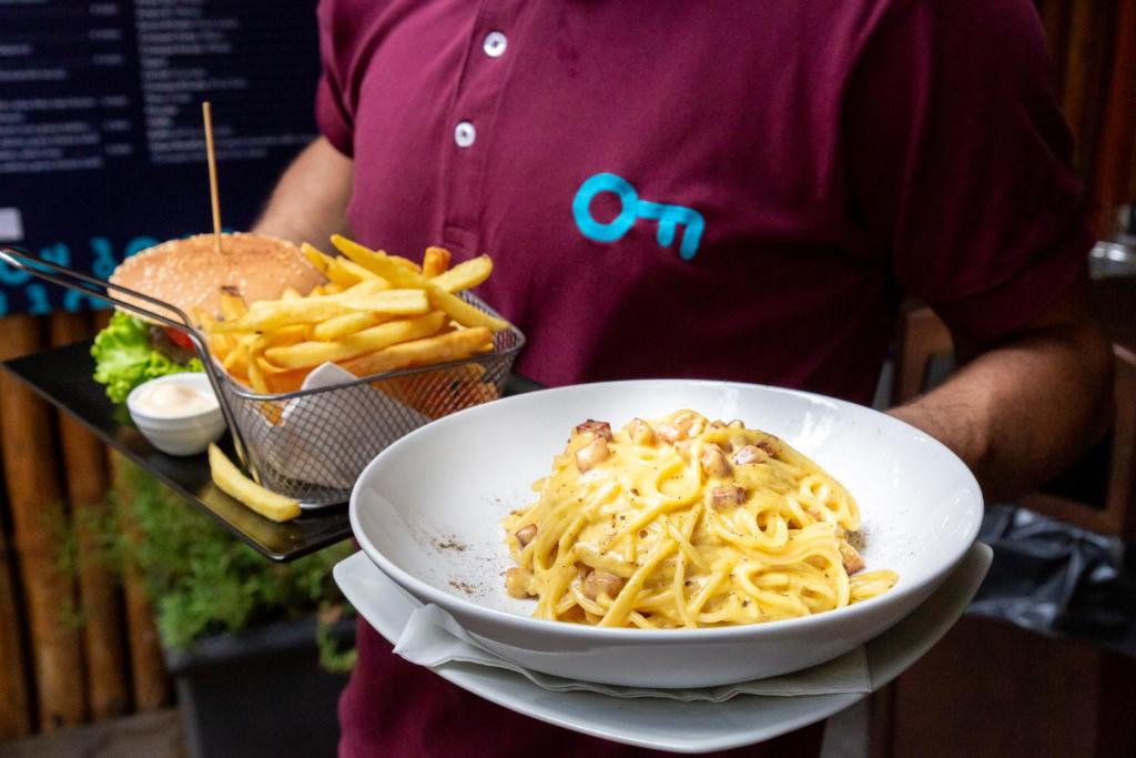 a person holding a bowl of pasta and a sandwich at Plus Florence in Florence