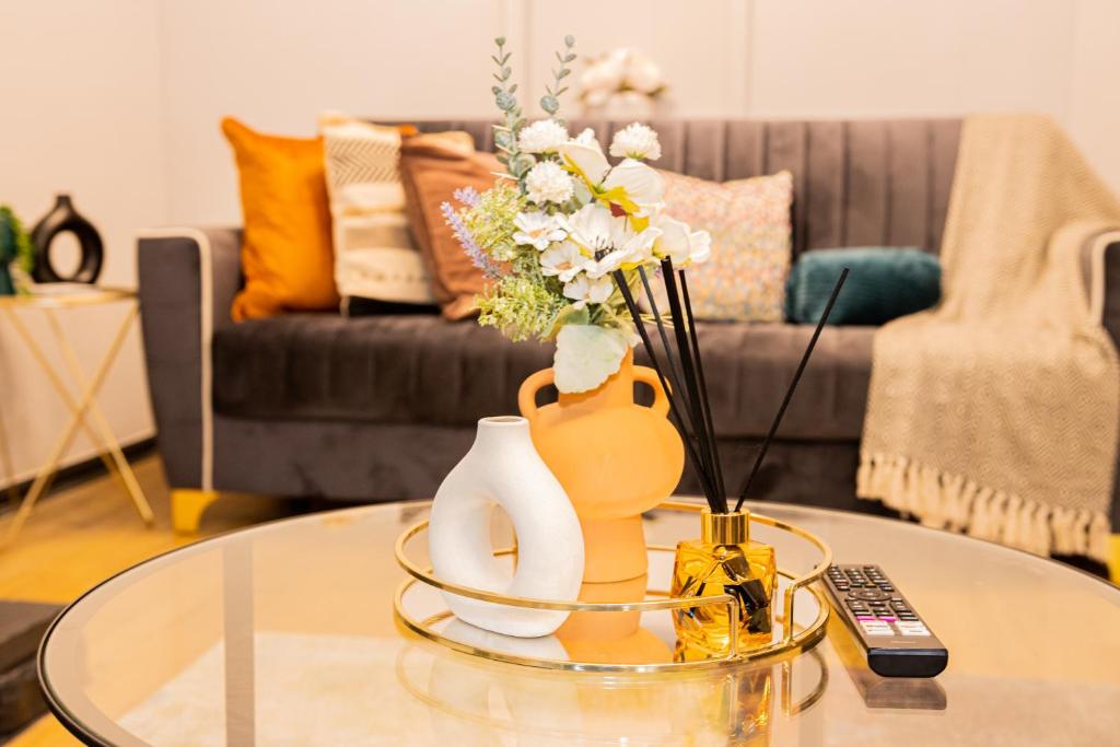 een woonkamer met een glazen tafel met een vaas met bloemen bij Luxurious 3-Bed House in Dudley - DY1 in Dudley