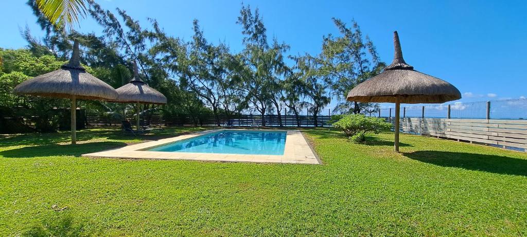 a backyard with a swimming pool and two umbrellas at Clair de Lune - Private 2 Bedrooms Beachfront Villa in Trou dʼ Eau Douce