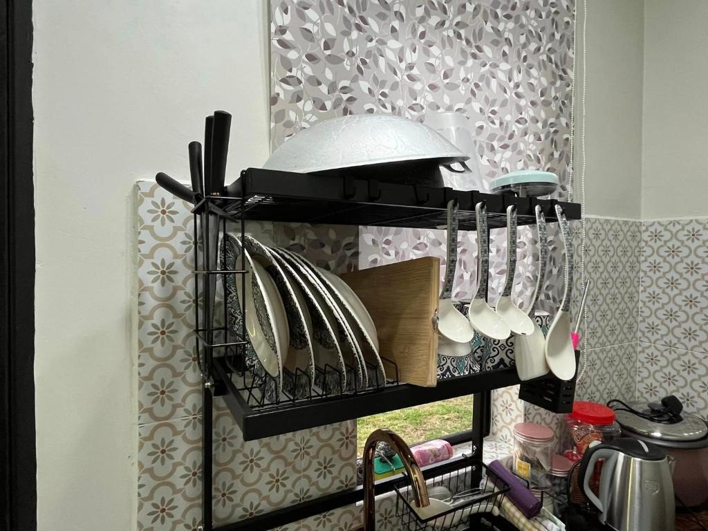 a kitchen shelf with plates and utensils on it at Rumah Armand 3 Bedroom with Swimming Pool Pengkalan Balak Tg Bidara Masjid Tanah Melaka in Masjid Tanah