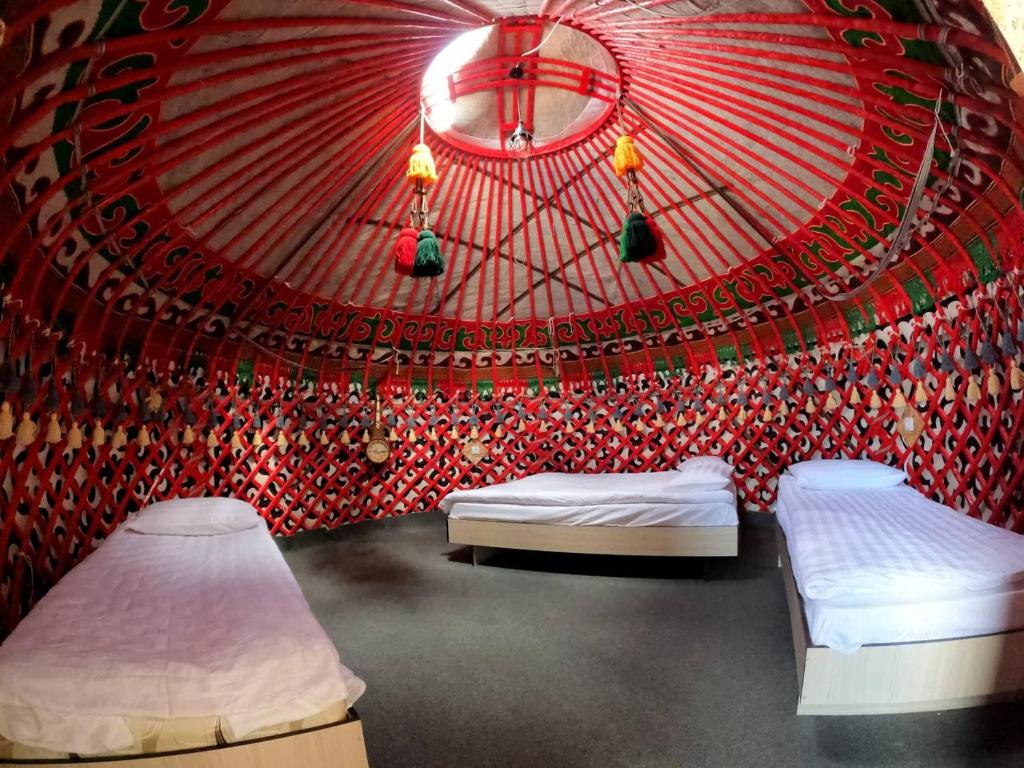 a room with two beds and a red wall at Royal Gate at Skazka Canyon in Tong