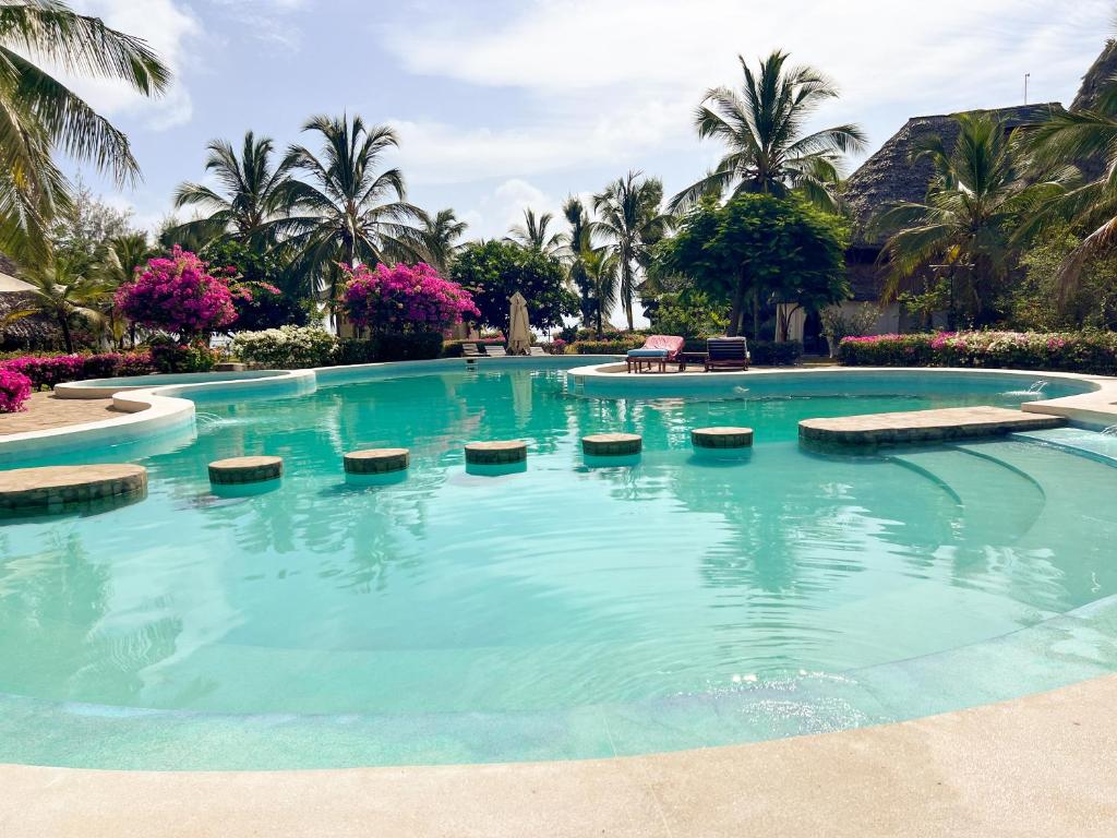 - une piscine d'eau bleue avec des palmiers dans l'établissement Harbour Key Cottages - House 19, à Malindi