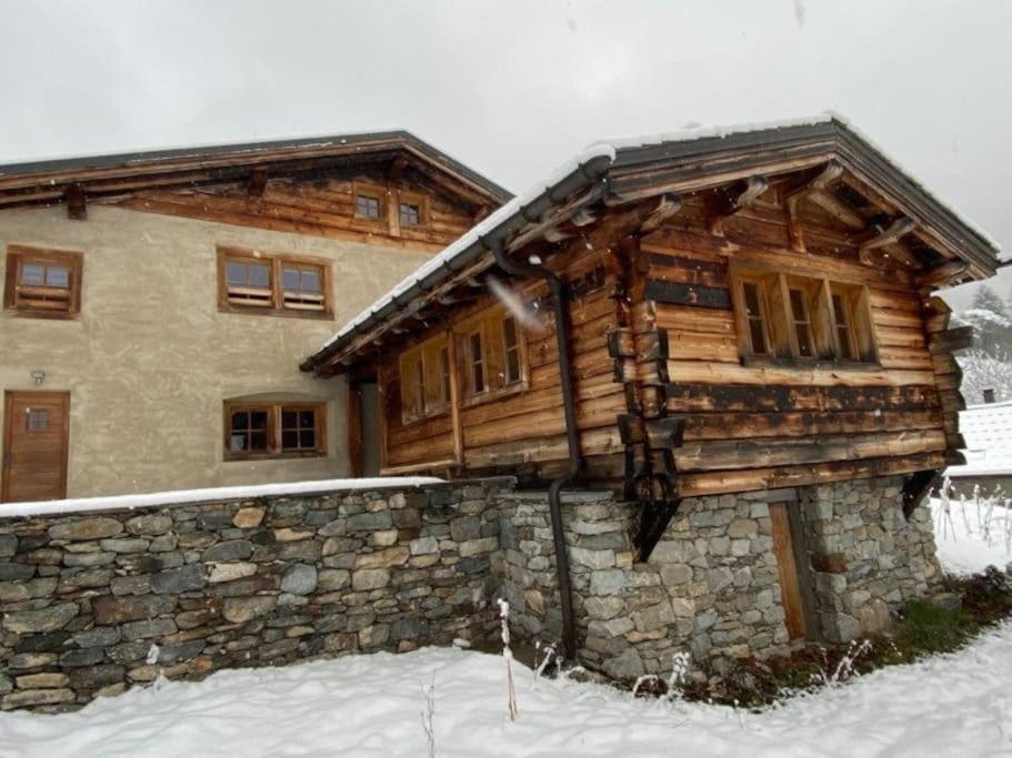 a log cabin in the snow with a stone wall at Gîte La Loriaz in Vallorcine